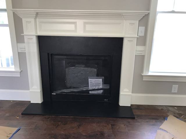 fireplace with a white mantel and black stone hearth