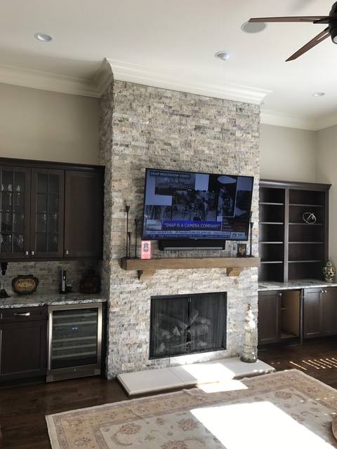 Traditional and Rustic Stone fireplace with a tv mounted above it.
